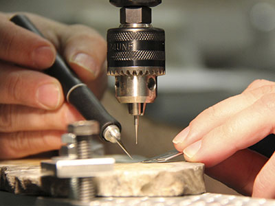 person examining a sample under a microdrill